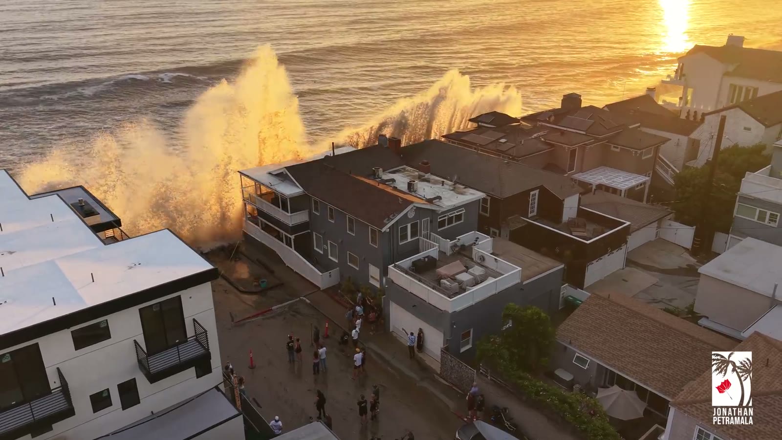 Storm waves crashing over beachfront homes at sunset
